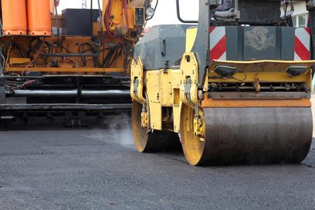道路施工现场工人铺设新沥青或沥青的道路施工施工道路工程中的推土机